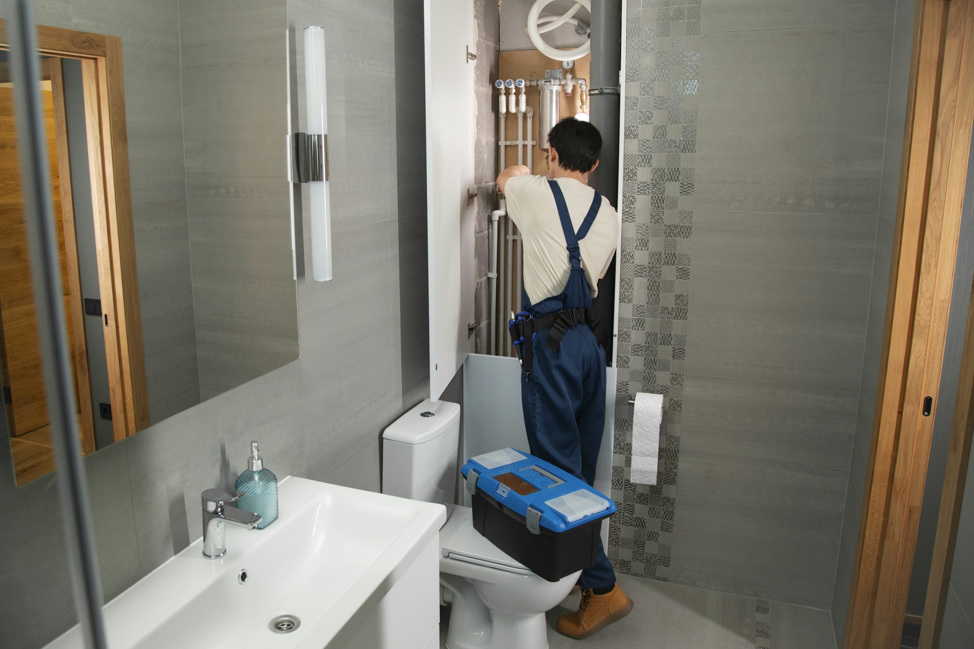Plombier avec sa caisse à outils, au travail dans une salle de bain